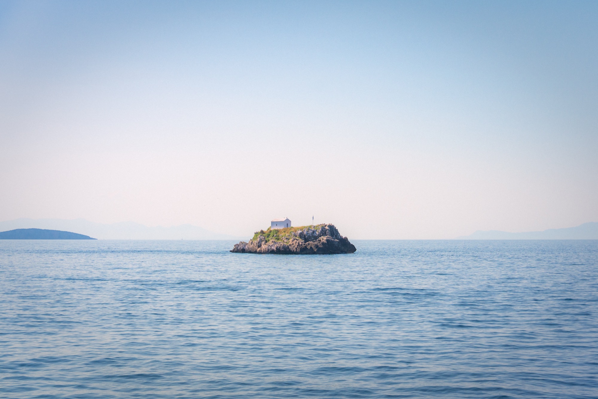 Small island with white chapel on calm waters