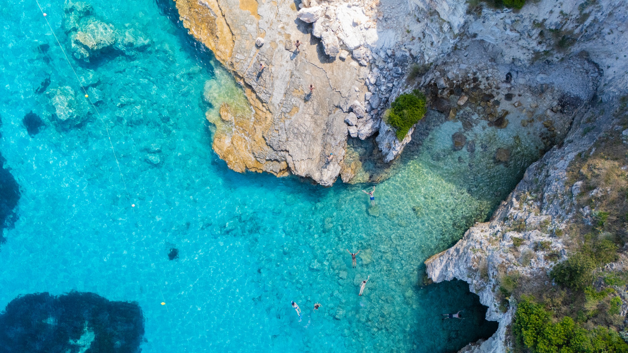 Top-down aerial of swimmers in turquoise cove
