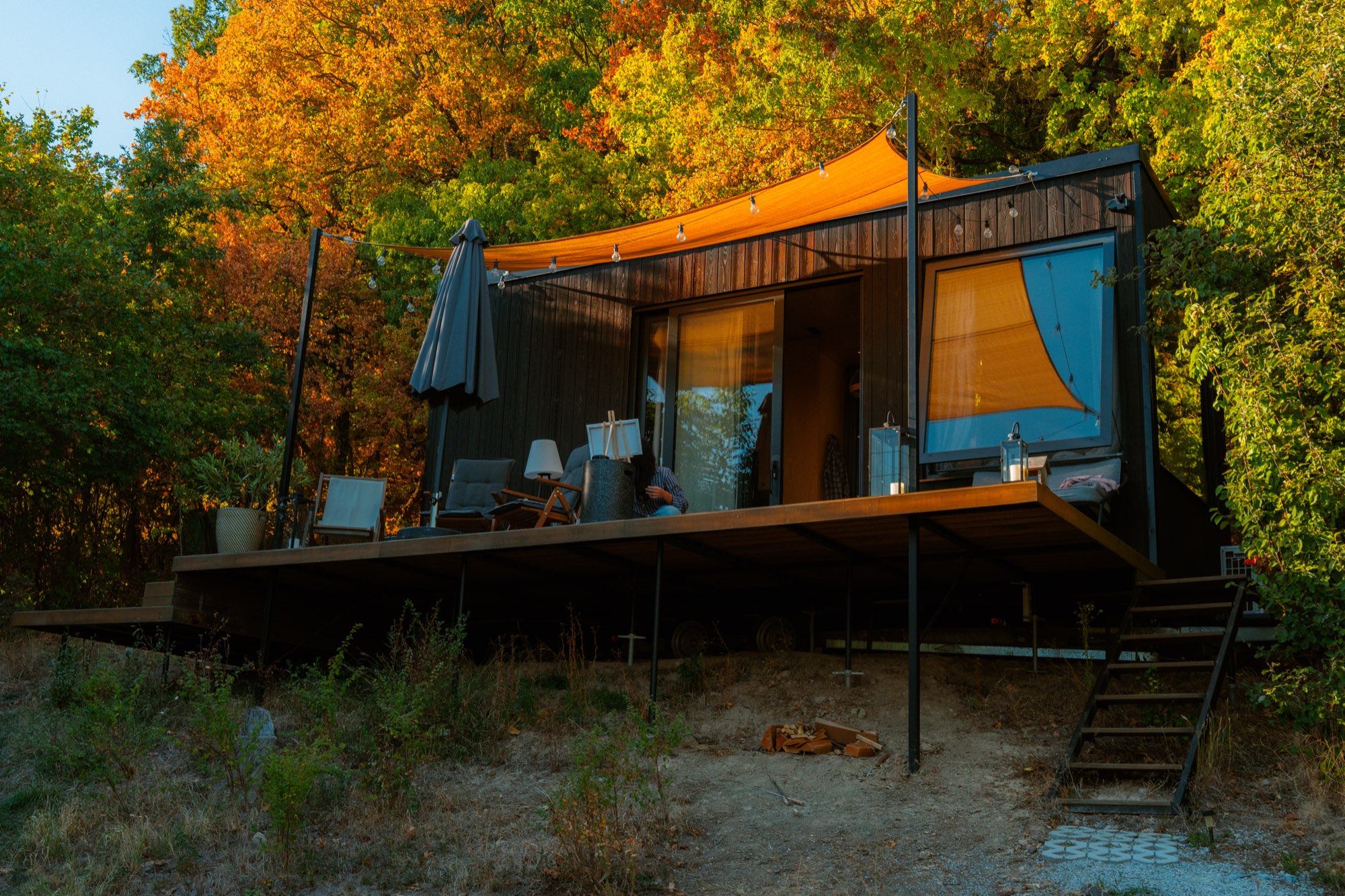 Wider view of the cabin and its steps against the autumn woodland