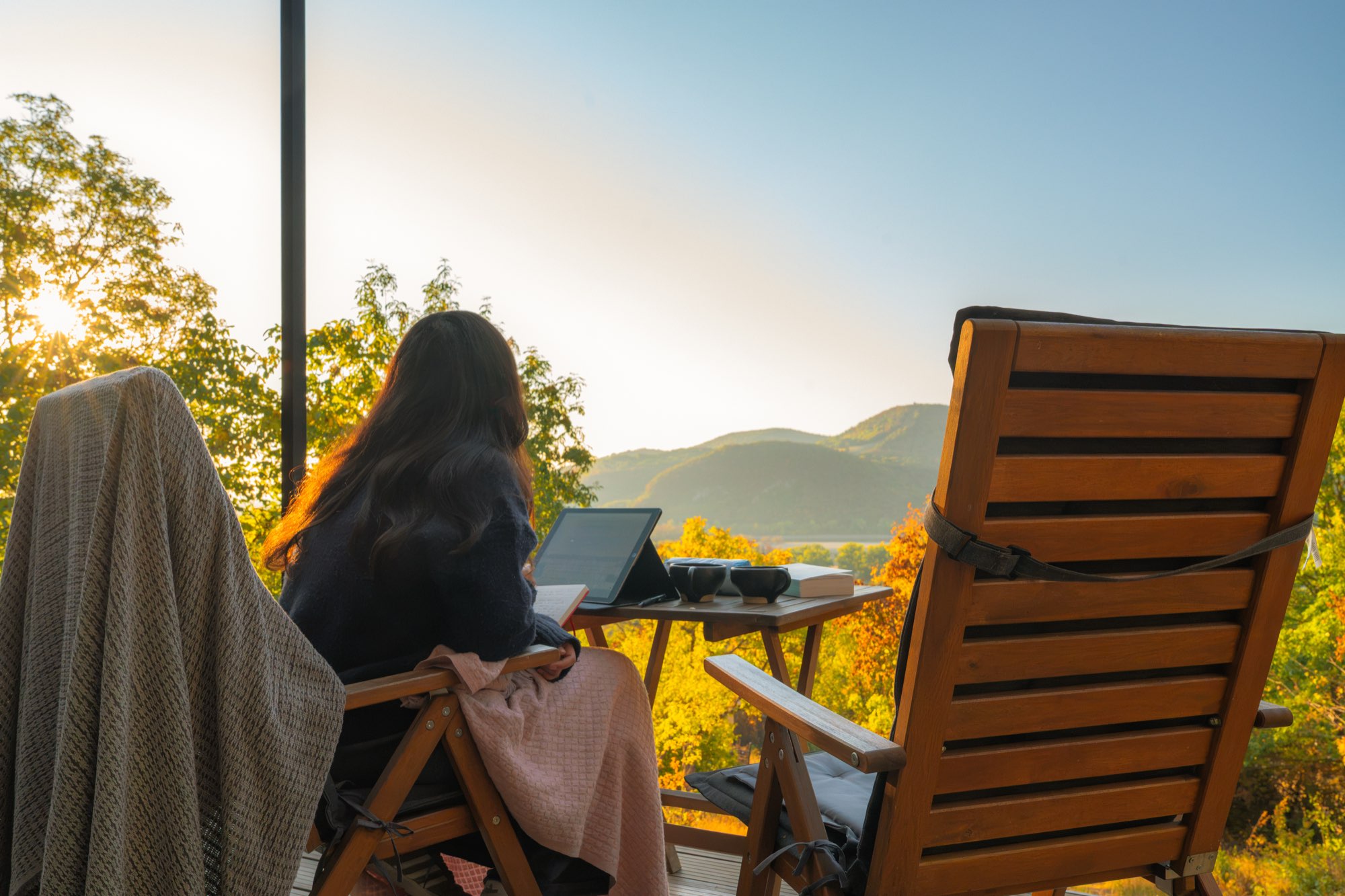 Two guests in deck chairs watching the sun come up over the valley