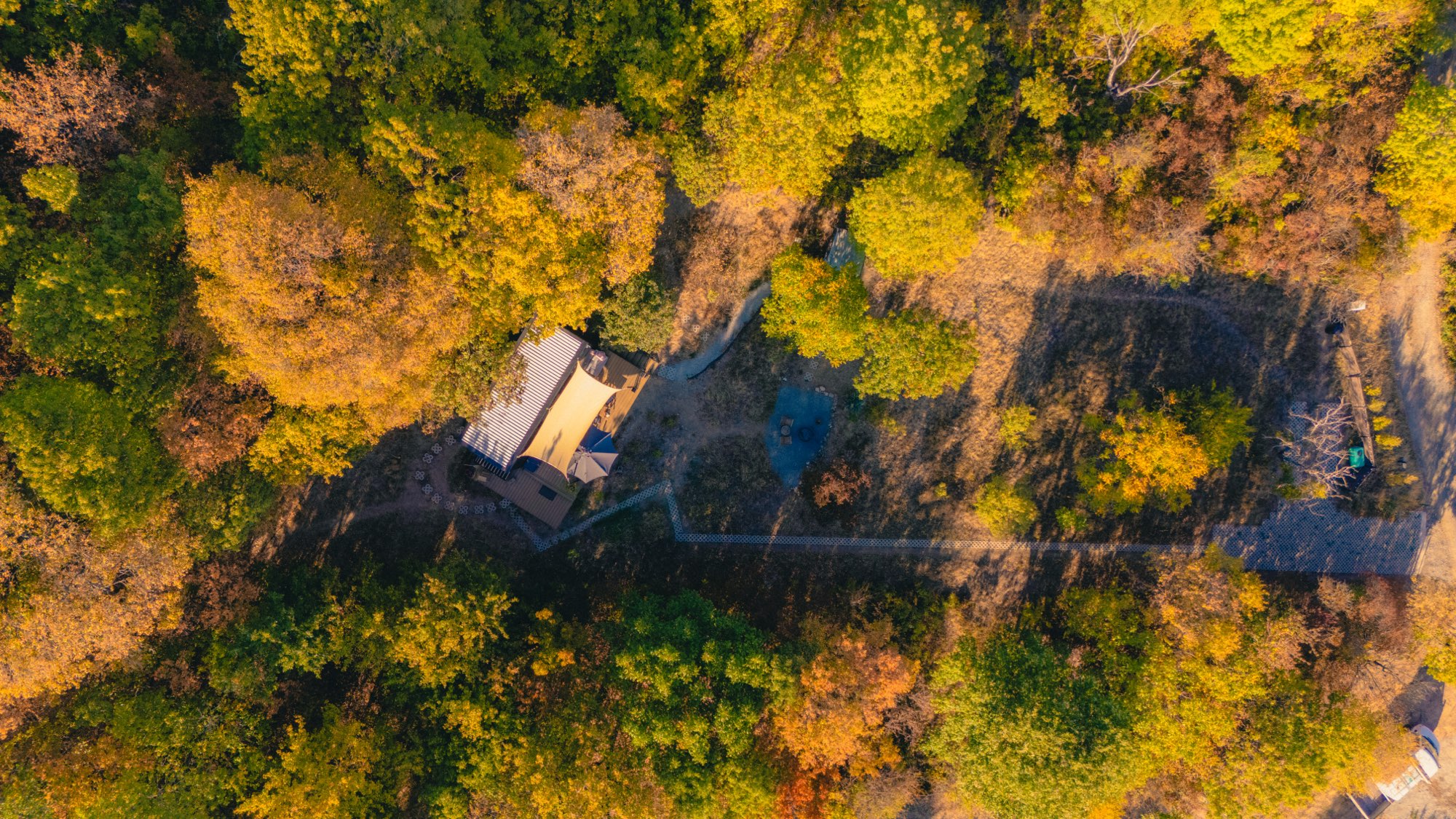 Top-down aerial of the cabin and its paths cut into the hillside