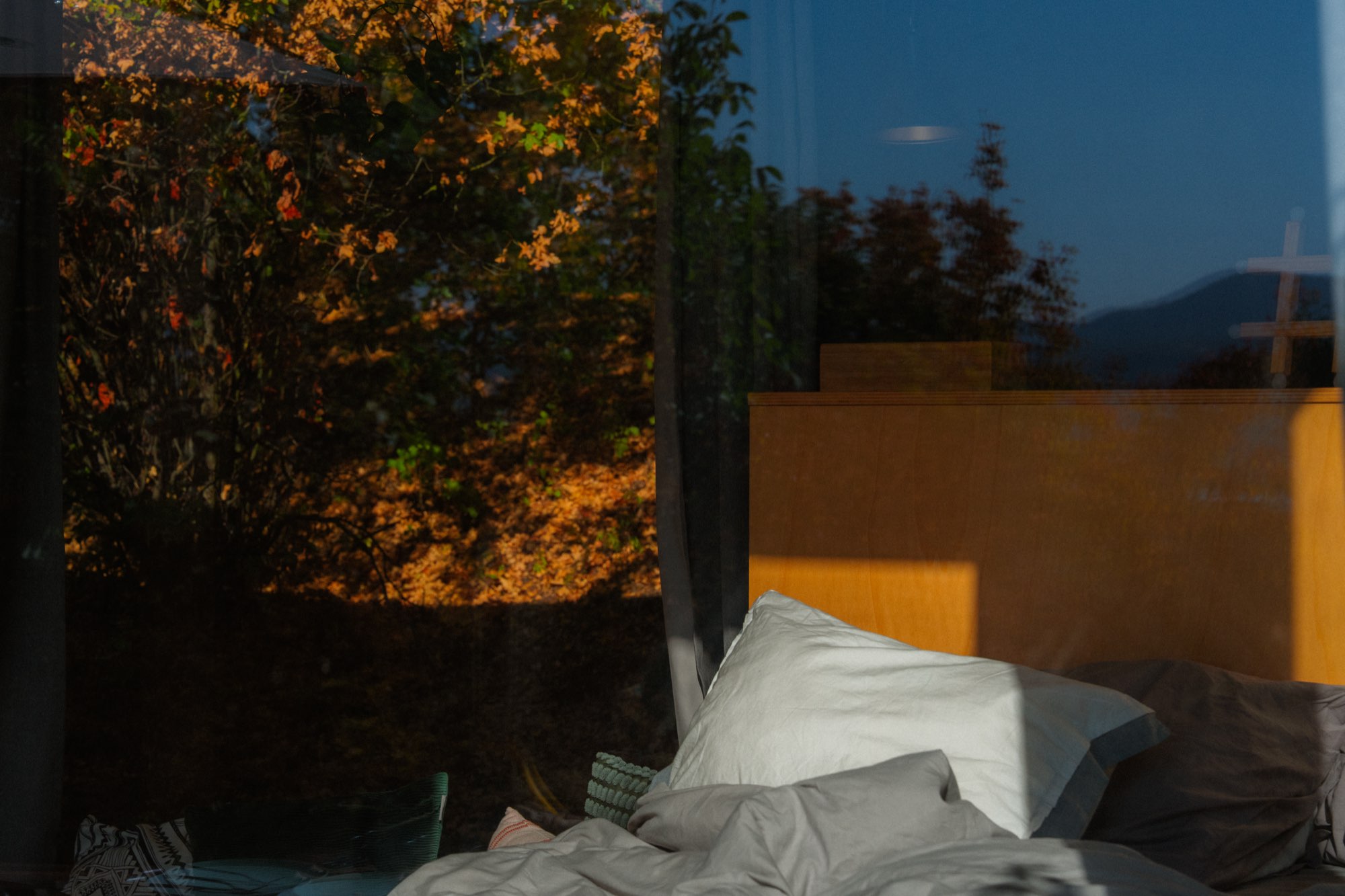 Bed beside the window as dusk settles over the valley