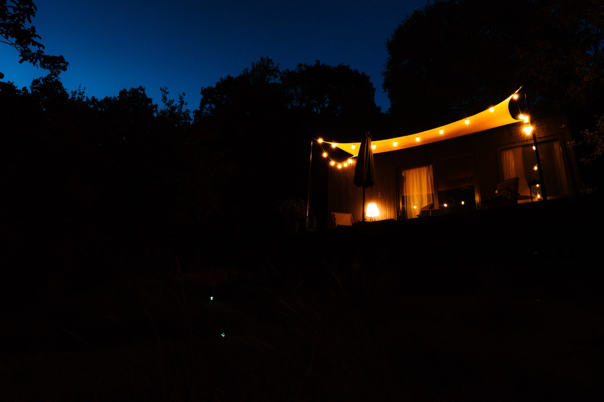 The cabin glowing on the dark hillside at night