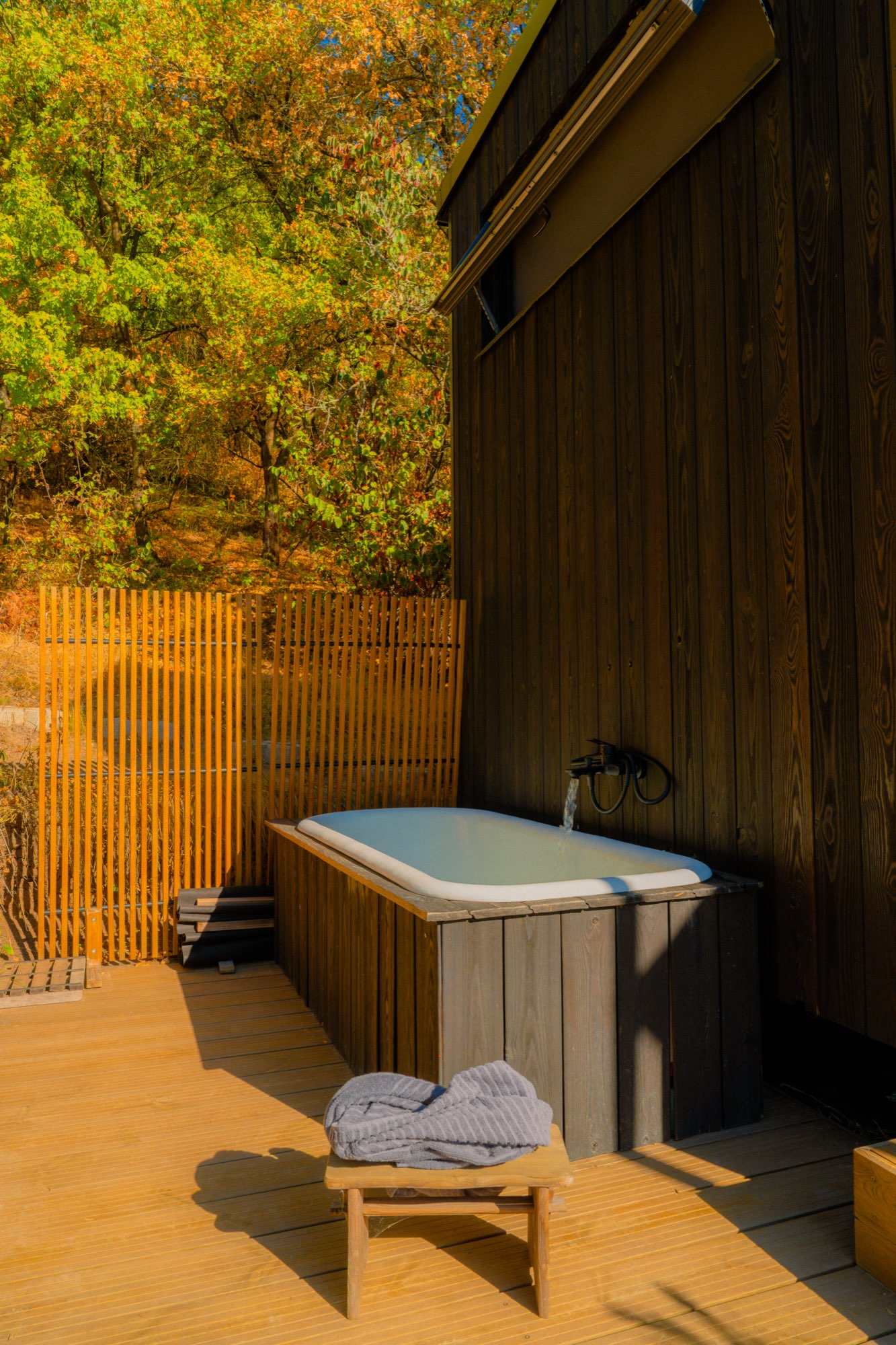 Outdoor bath on the deck with towels folded on a stool