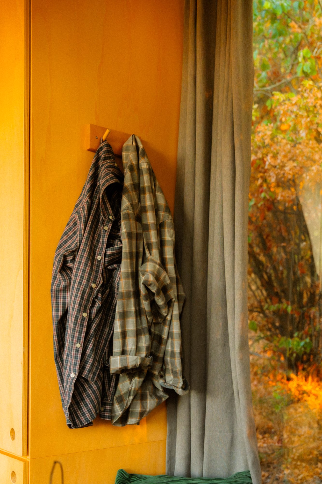 Checked shirts hanging on a peg against the yellow cabin wall